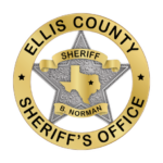 Gold badge with black text that says Ellis County Sheriffs Office Sheriff B. Norman with silver start and gold state of texas with black star on ellis county